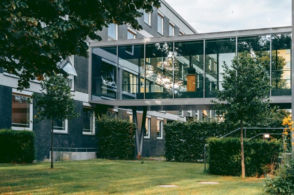 Contemporary architecture with a connecting glass walkway in a lush garden.